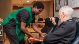 Carer serving a cup of tea and a biscuit to a dementia care resident at Riseley House Care Home in Macclesfield